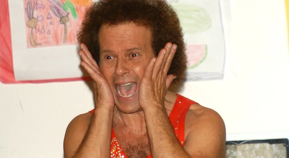 Richard Simmons holding his hands on either side of his face and screaming.
