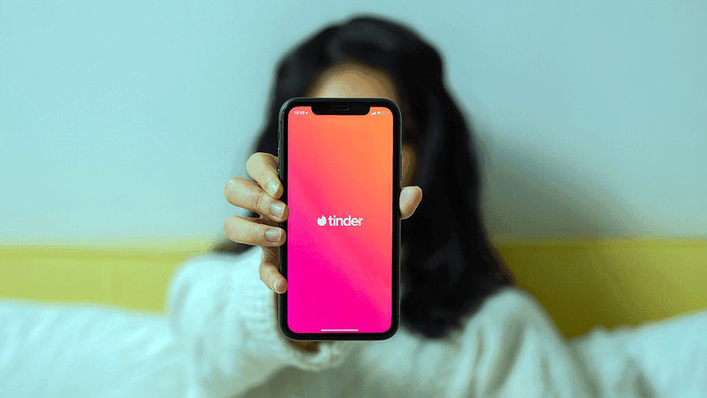 Woman holding up phone with Tinder app. Photo by cottonbro from Pexels.