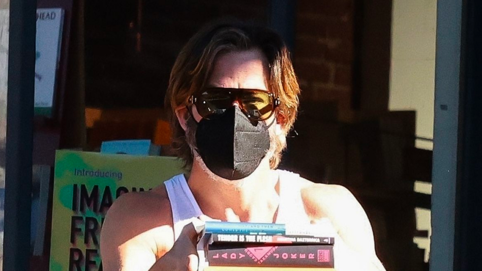 Chris Pine leaving a bookstore with shades, a mask, and a stack of books.