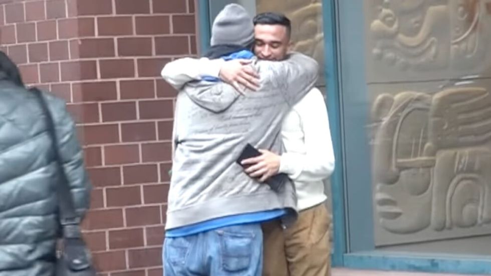 Waqas Shah hugs a homeless man in a hoodie on a nyc street