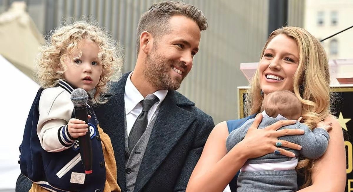 Ryan Reynolds and Blake Lively holding their two young children and smiling.