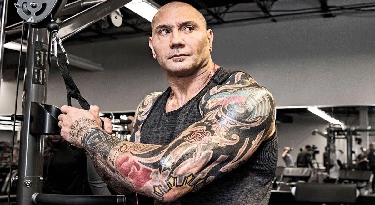 Dave Bautista showing off muscles and tattoos in the gym.