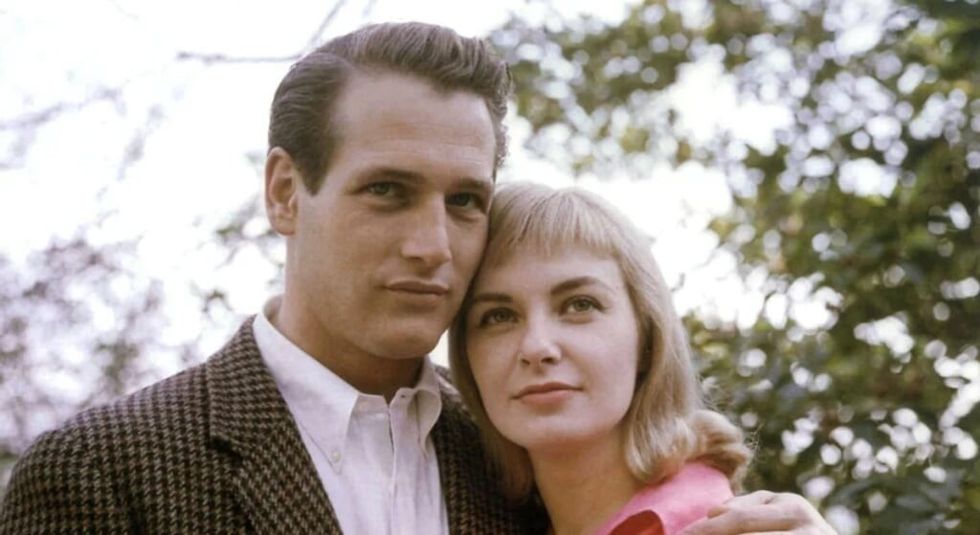 A young Paul Newman with wife Joanne Woodward hugging.