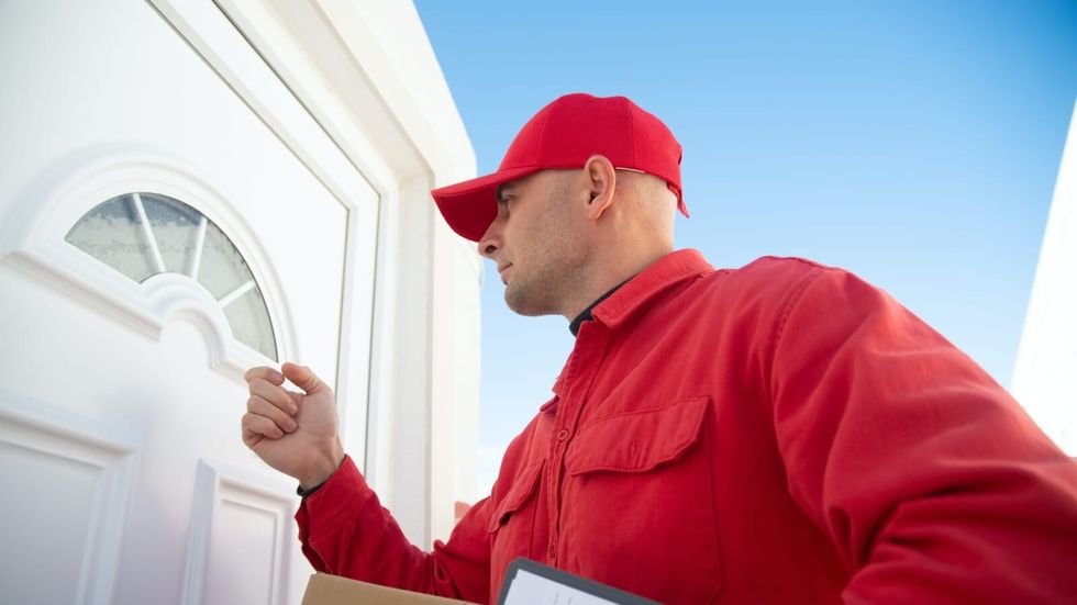 man in red outfit knocking on white door