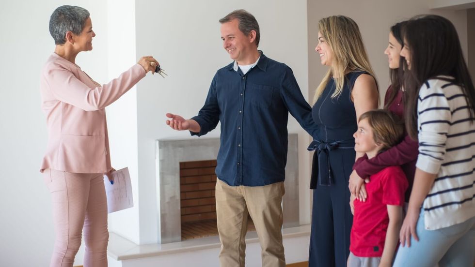 woman handing keys to a house to a man and his family