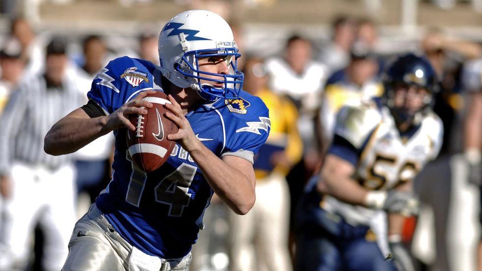 man in blue uniform and helmet holding a football