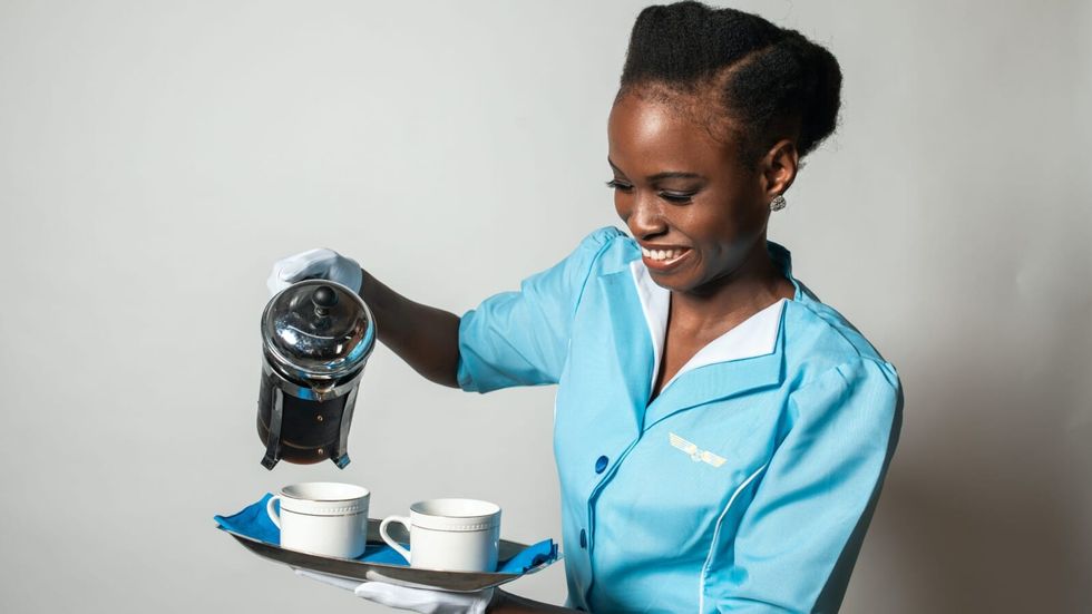 woman wearing a blue uniform pouring coffee into cups