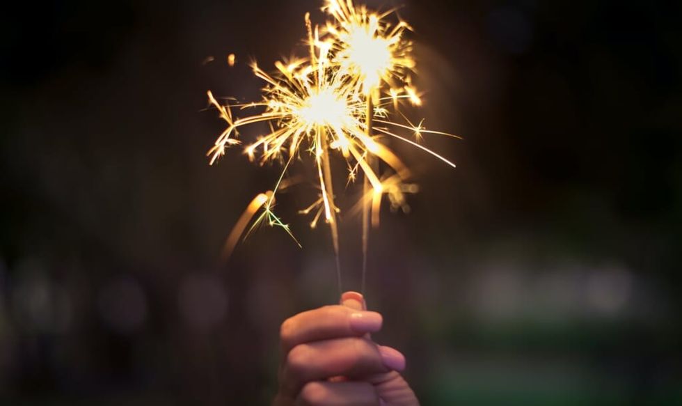 person holding a lit sparkler in their hand
