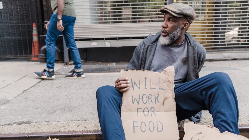 homeless man sitting on the sidewalk