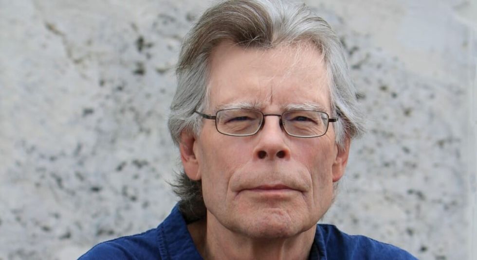 Stephen king with white hair looking at the camera.