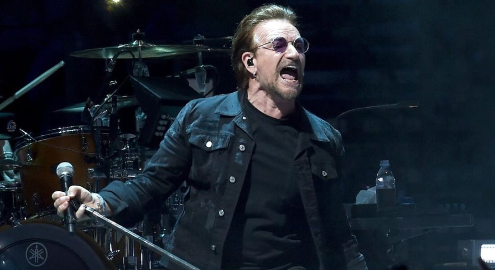 Bono singing on stage holding microphone.