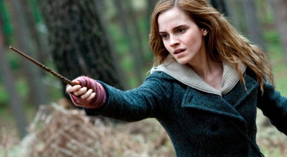 Emma Watson as Hermione in Harry Potter holding her wand and casting a spell.