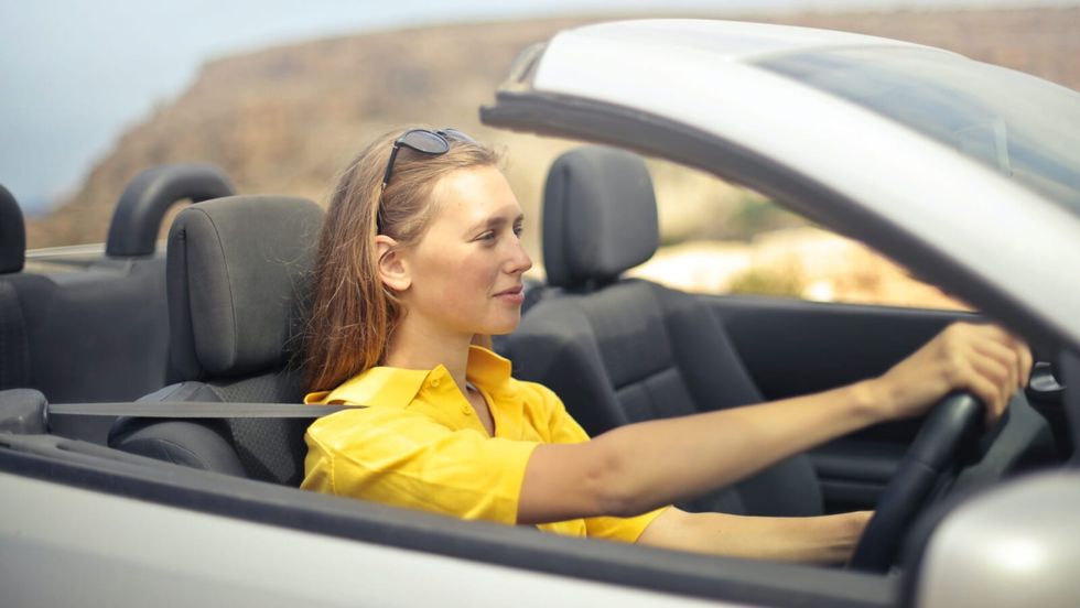 woman in a yellow shirt driving a car
