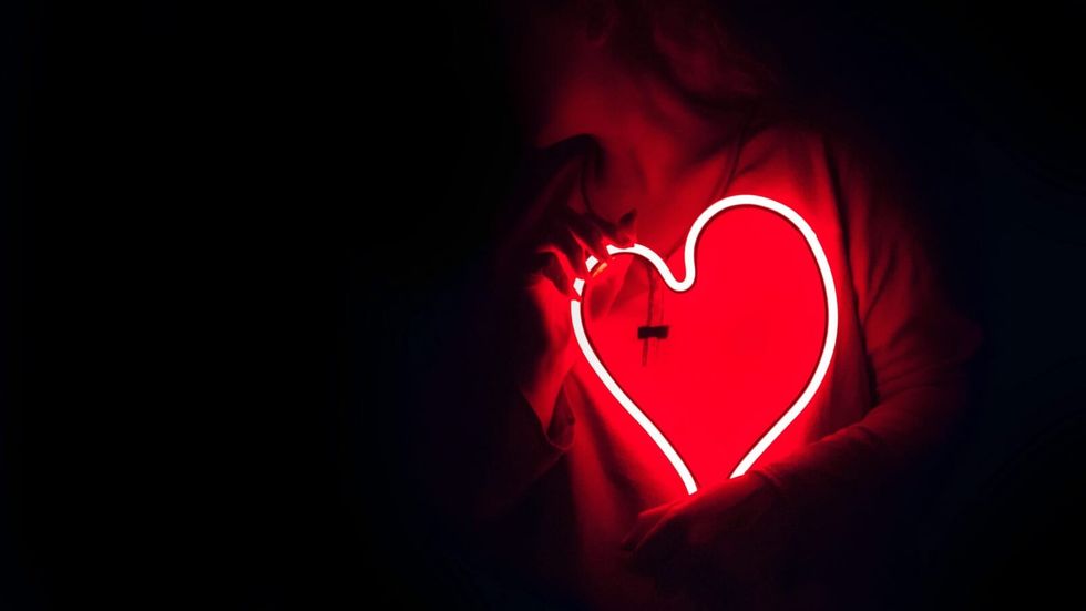 woman holding a neon heart sign
