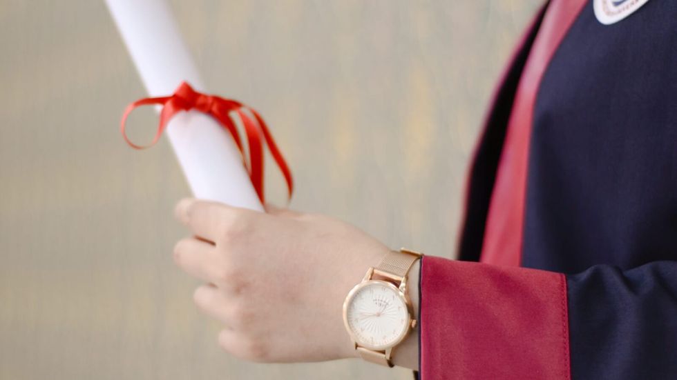 person holding his degree in a graduation gown