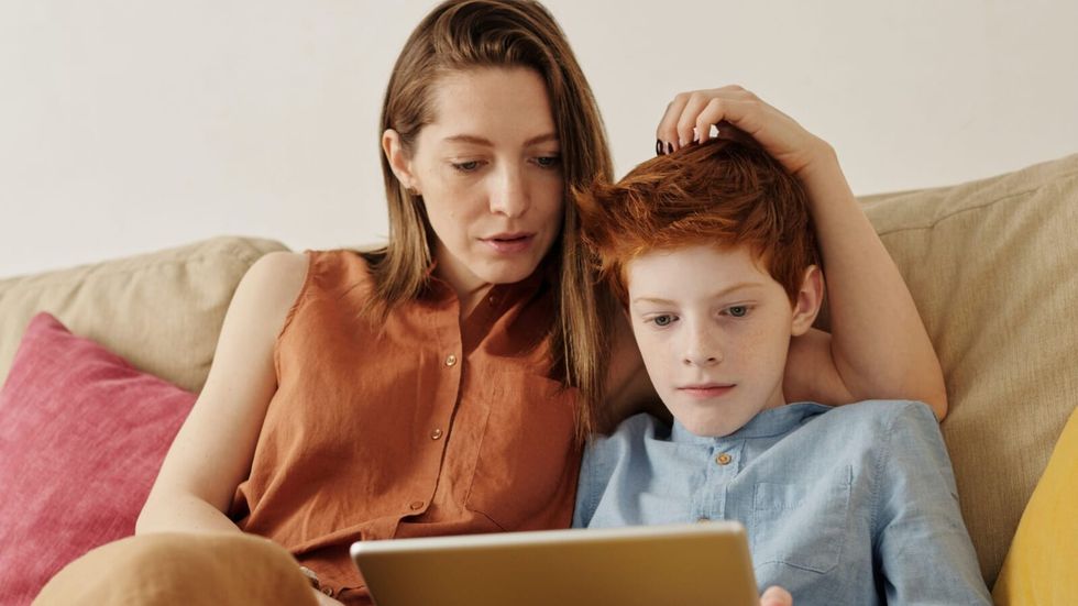 mom and son watching something on an ipad on the couch