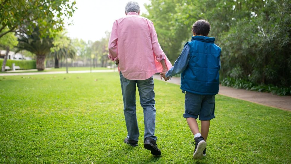 elderly man holding a hand and walking with younger boy
