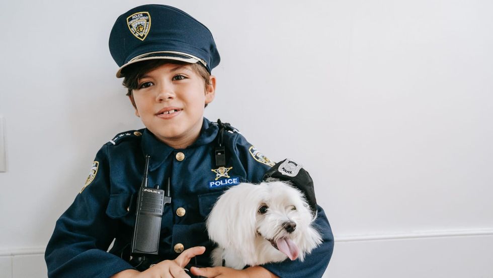 little boy wearing a police costume and holding a dog