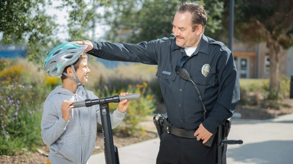 police officer patting the head of a smiling young boy