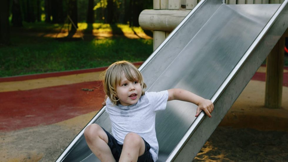 little boy playing on playground slide