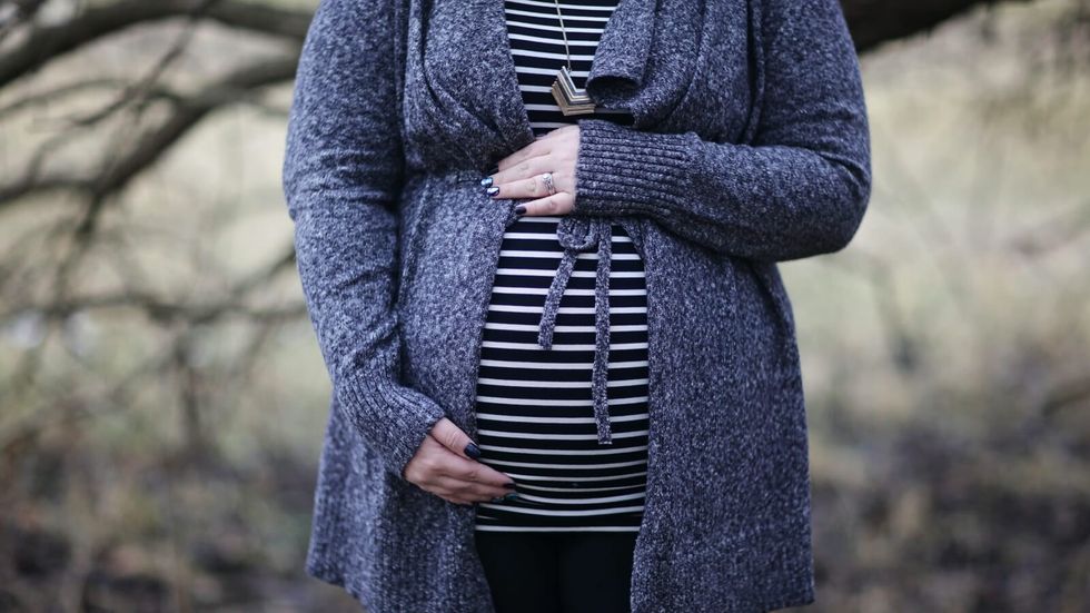 pregnant woman in a striped shirt and blue cardigan