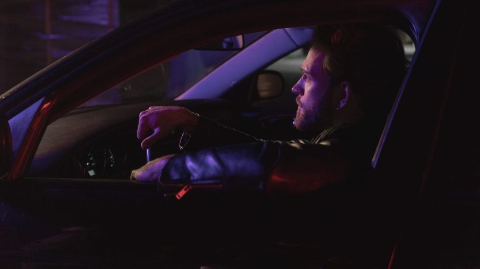 man in leather jacket driving at night