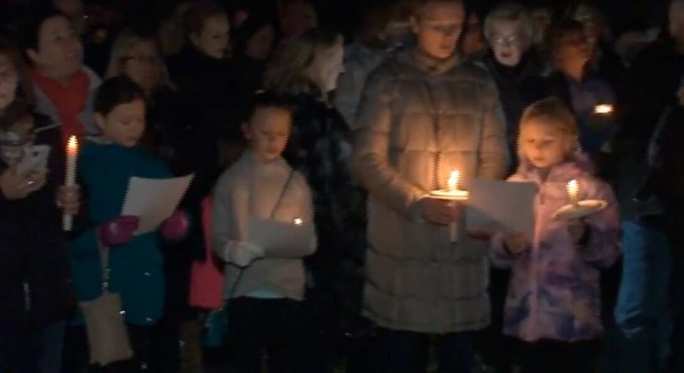 A group of residents holding candles and singing on Christmas.