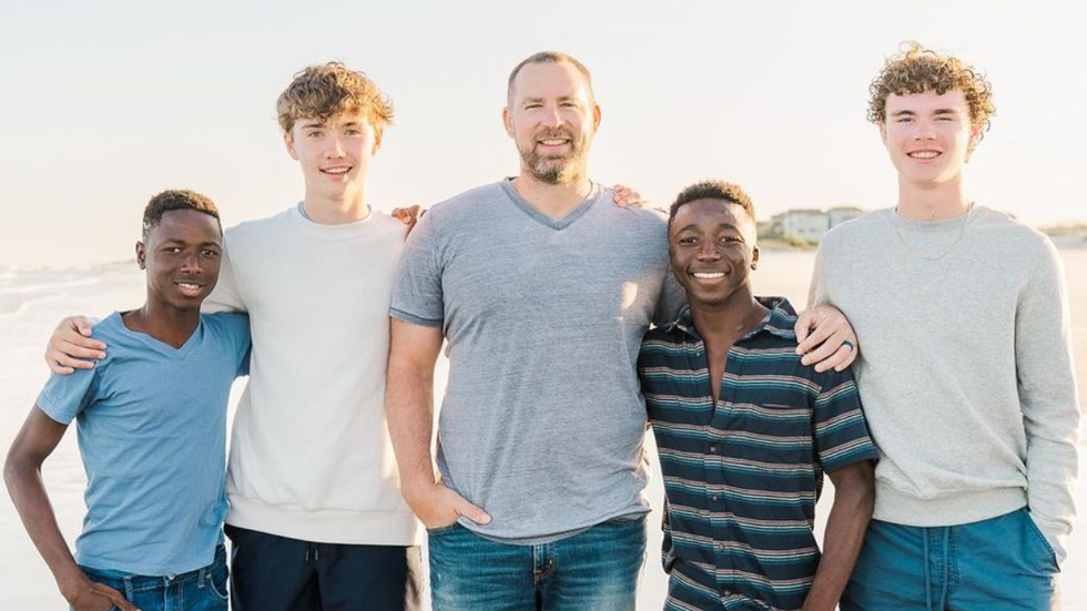 five men standing on a beach