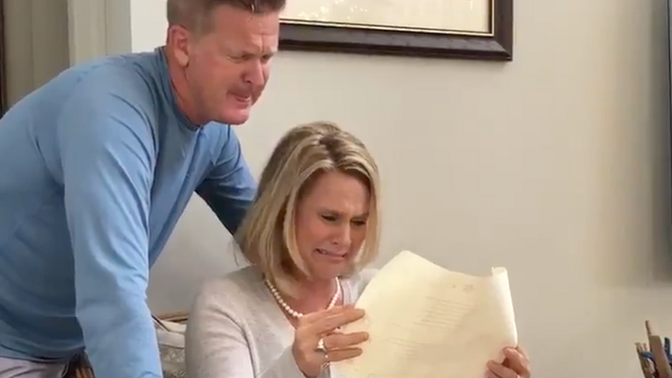 a man and a woman looking at a piece of paper and crying