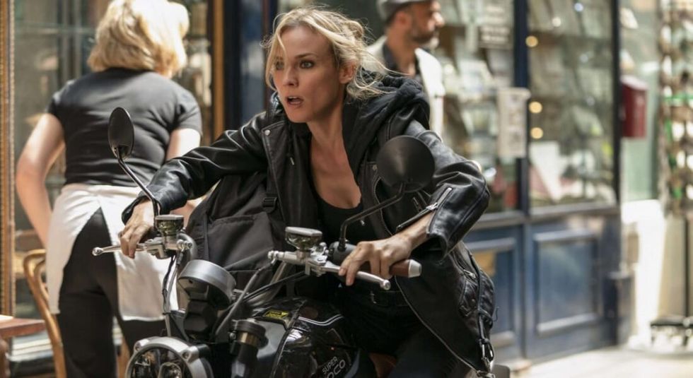 Diane Kruger in a black leather jacket riding a motorcycle in The 355.
