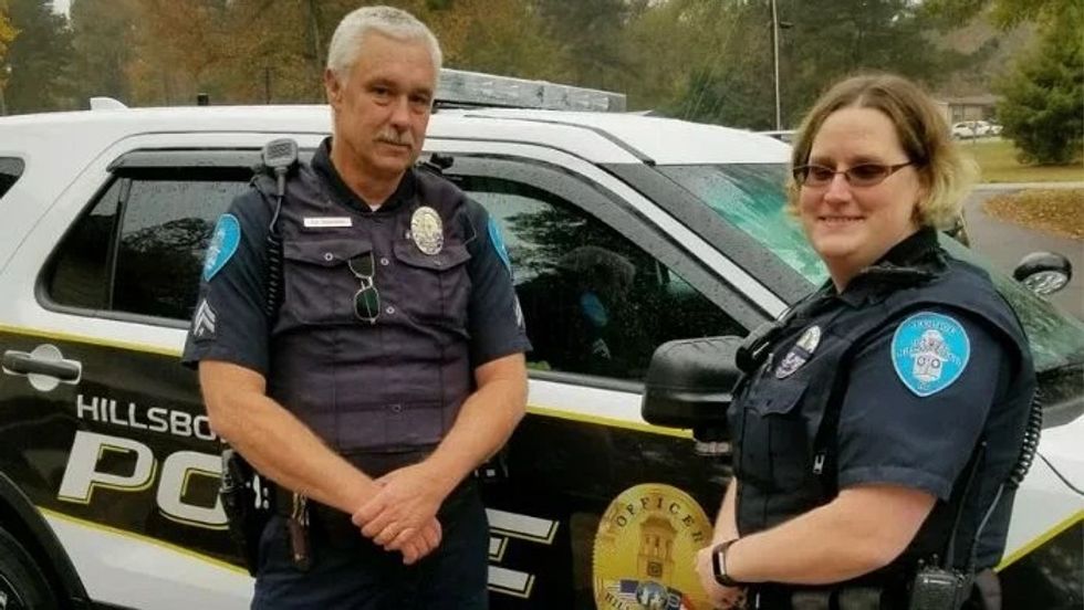 two police officers standing next to a cop car