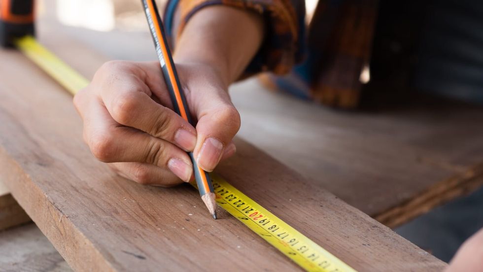 person using a pencil and a measurement tape