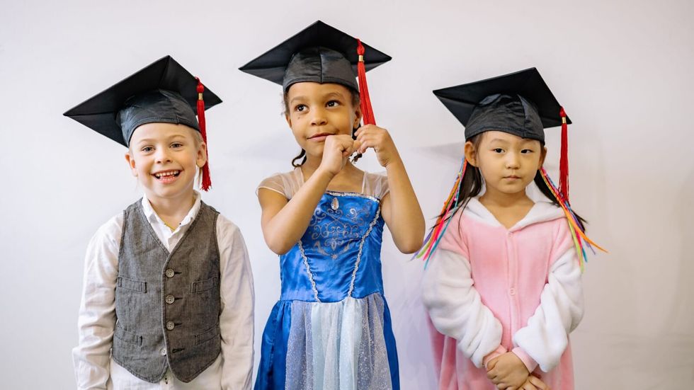 three children wearing graduation caps