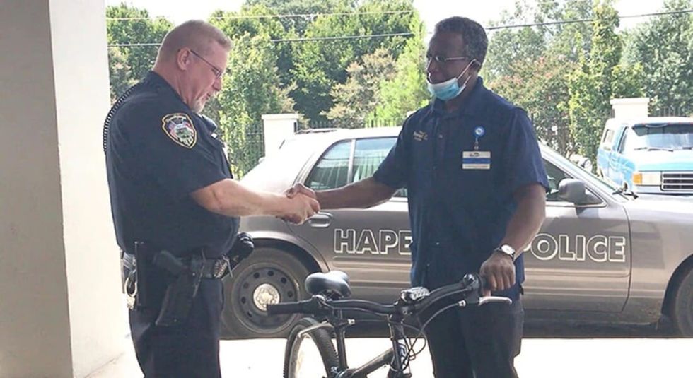 Police officer giving a free bike to man in need and shaking hands.