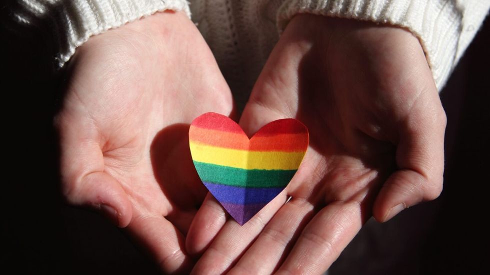 woman holding a rainbow heart in her hands