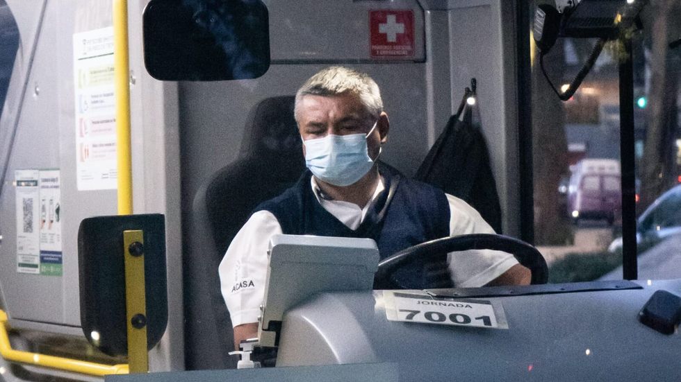 man wearing a face mask and driving a bus