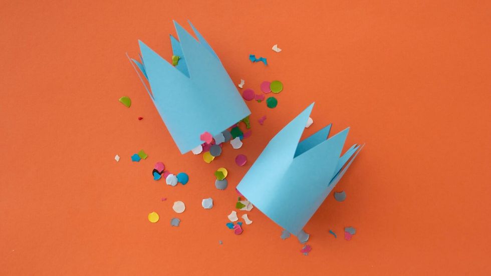 two blue paper crowns on a orange background