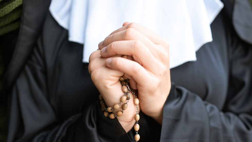 nun praying with folded hands
