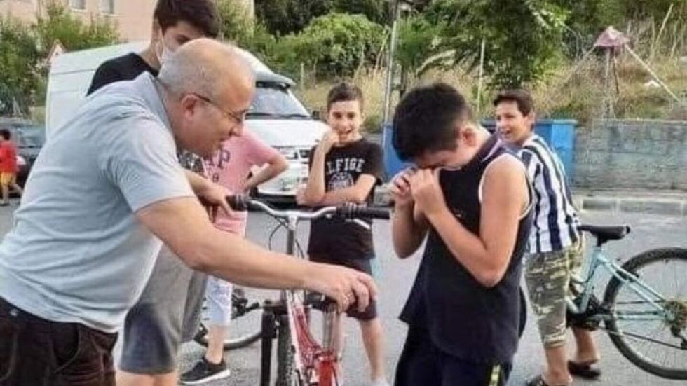 older man holding a bike and a little boy crying