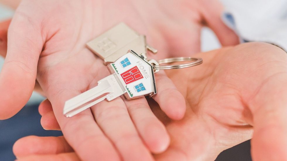 people holding a house shaped key in their palm
