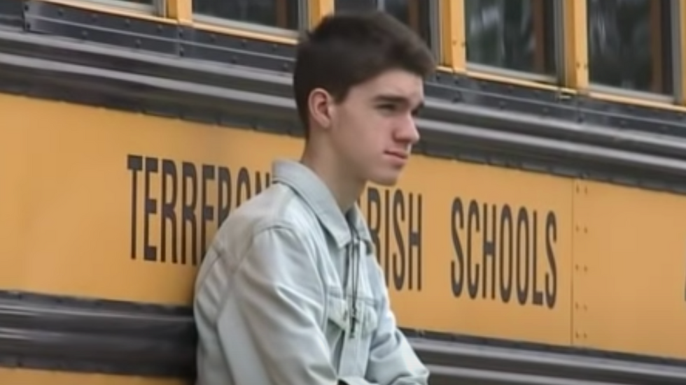 boy standing next to a school bus
