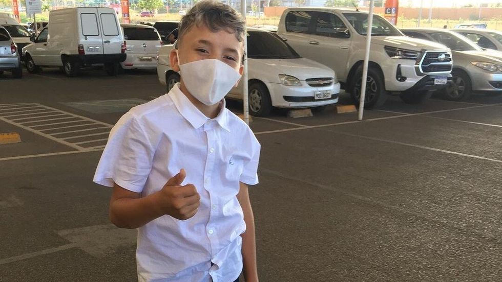 little boy wearing a white shirt and a mask