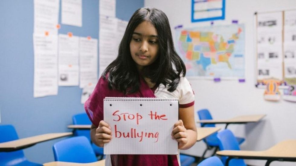 girl holding a sign which says "stop bullying"