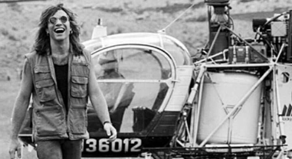 Black and white image of Bon Jovi walking away from a helicopter.