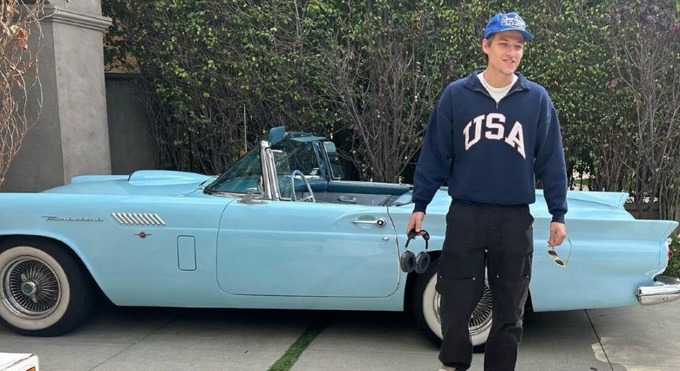 Jake Bongiovi standing in front of blue convertible, 