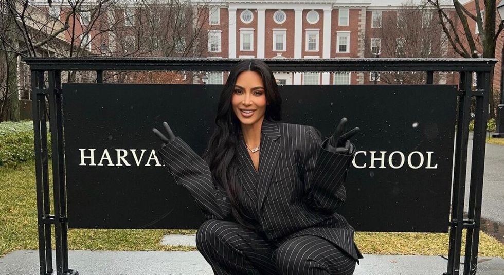 Kim Kardashian posing in front of Harvard sign. 