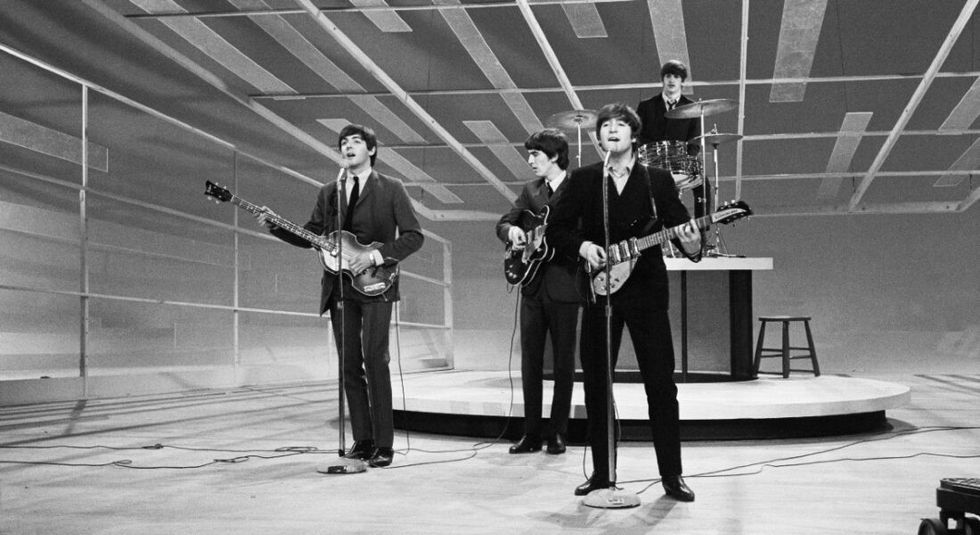 Black and white photo of The Beatles playing on the Ed Sullivan Show.