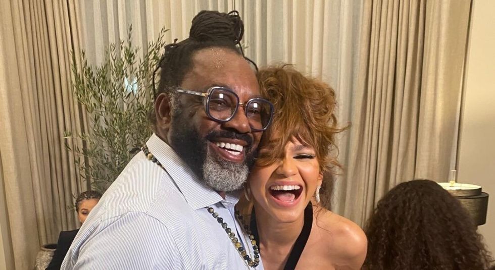 Zendaya and her father smiling at the camera.