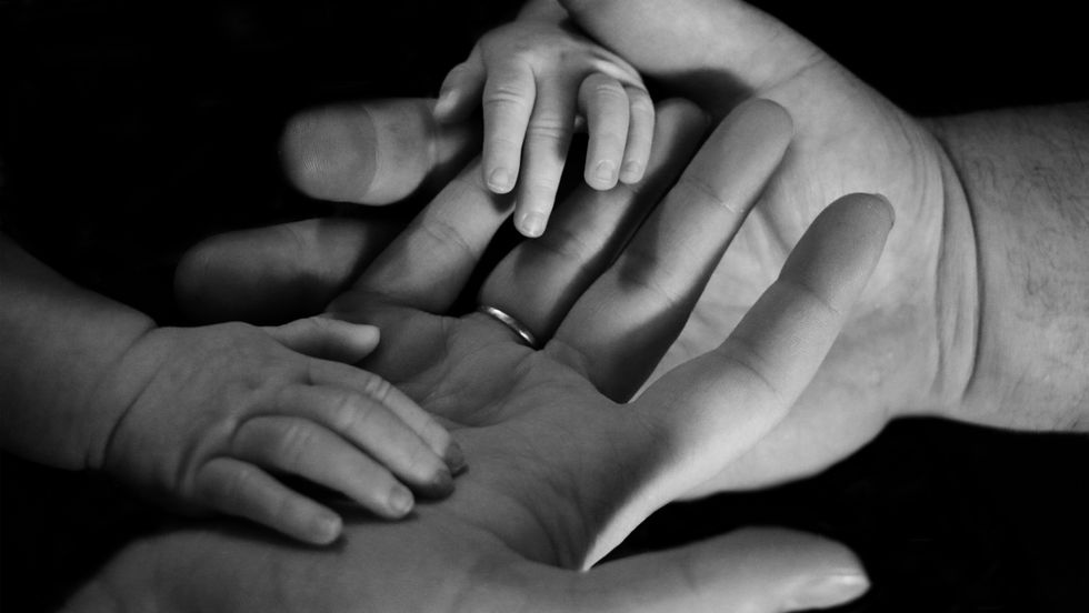 people holding a baby's hand
