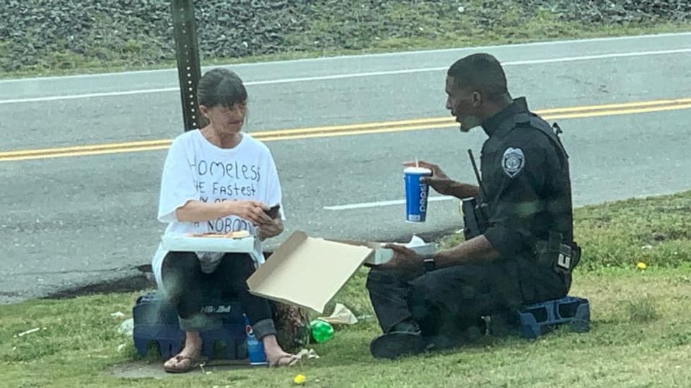 woman and a police officer sitting on the ground and eating pizza